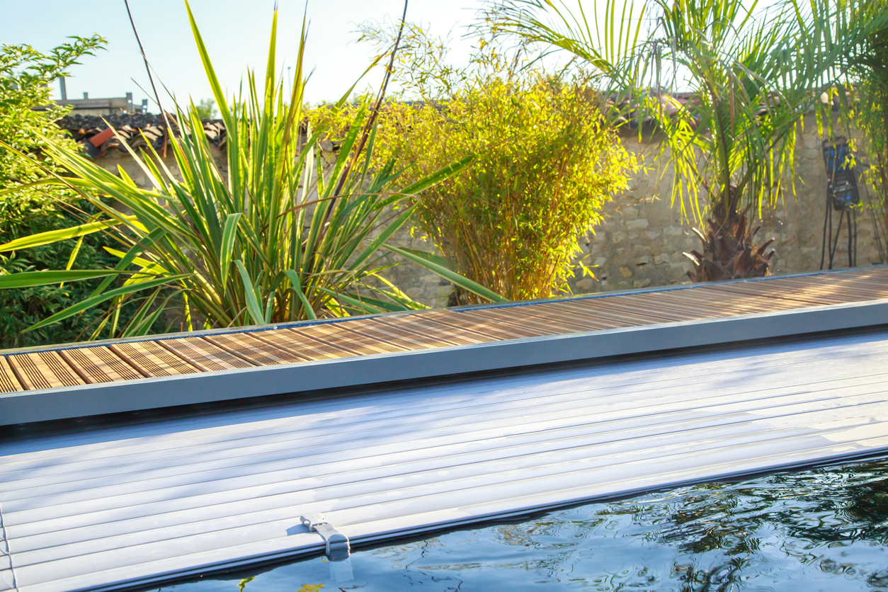 un volet roulant sur une piscine avec une terrasse en bois