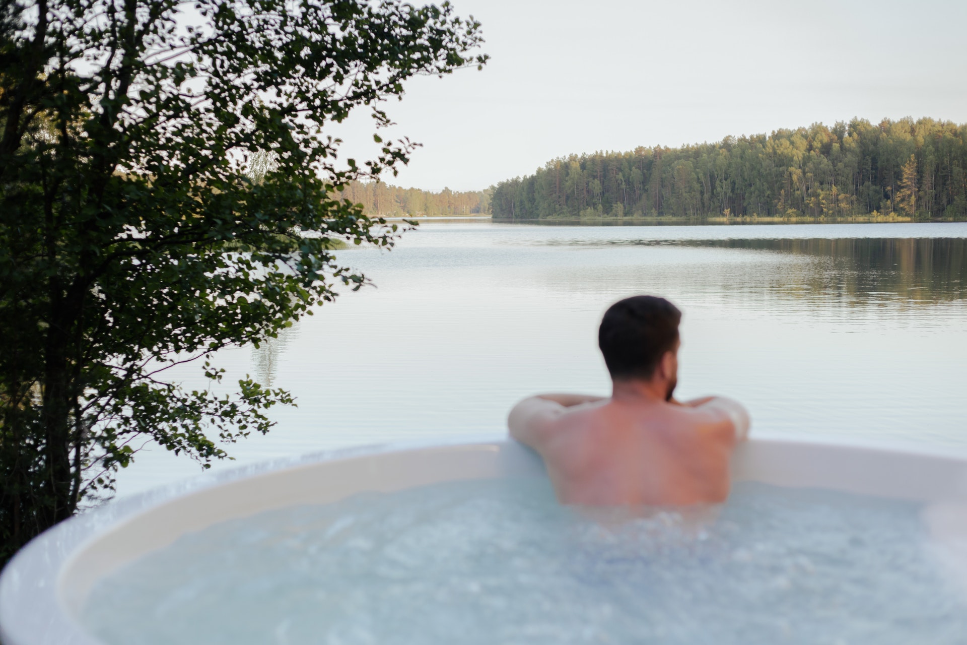 homme dans jacuzzi allumé vue sur lac