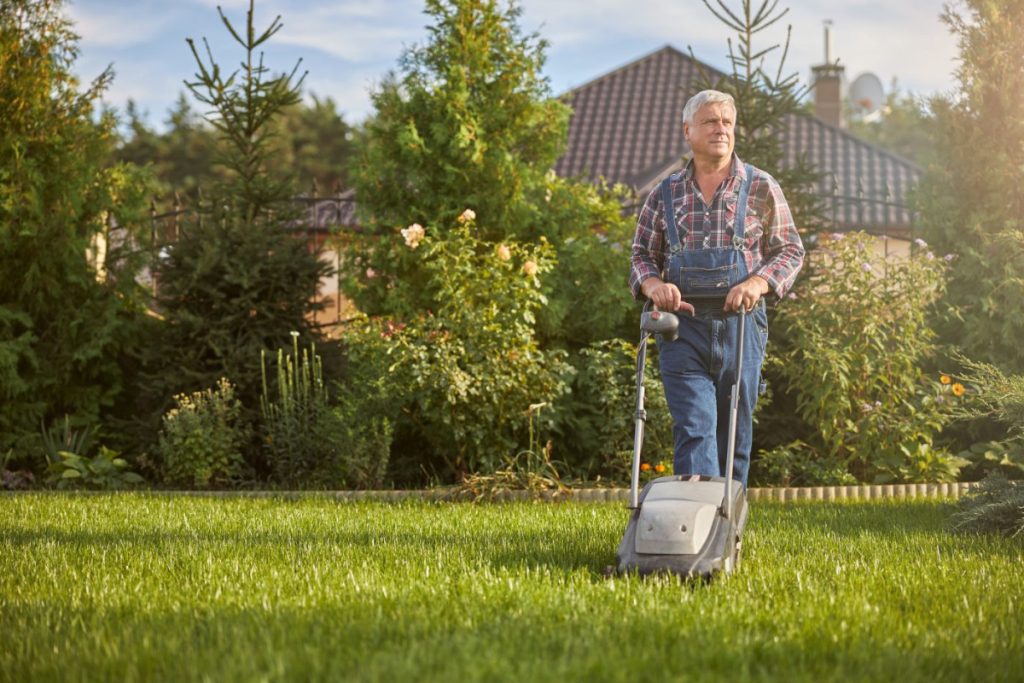 Homme qui passe la tondeuse dans son jardin