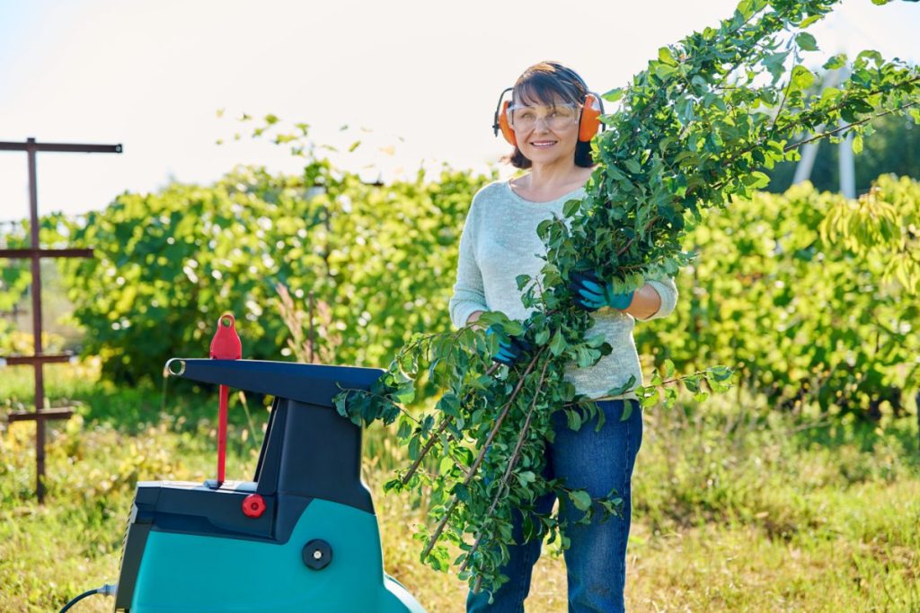 Femme utilisant une broyeuse à végétaux
