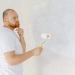 Devenez l'artiste de la peinture : Guide ultime pour des retouches parfaites man-painting-walls-with-paint-roller-handyman-ho-2022-11-12-15-58-05-utc